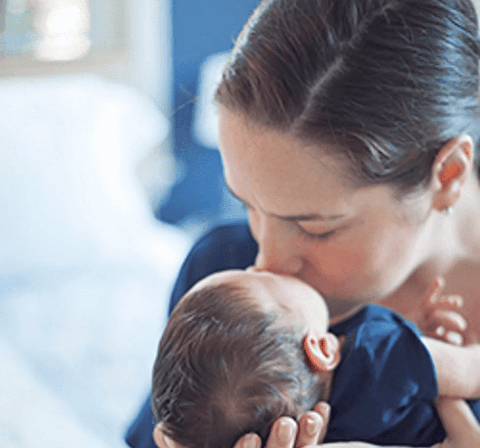 woman kissing newborn baby