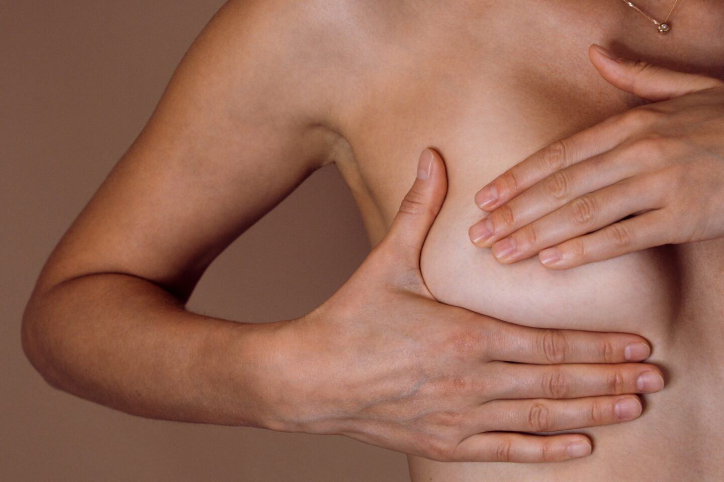 woman checking breast with hand for lumps or signs of breast cancer