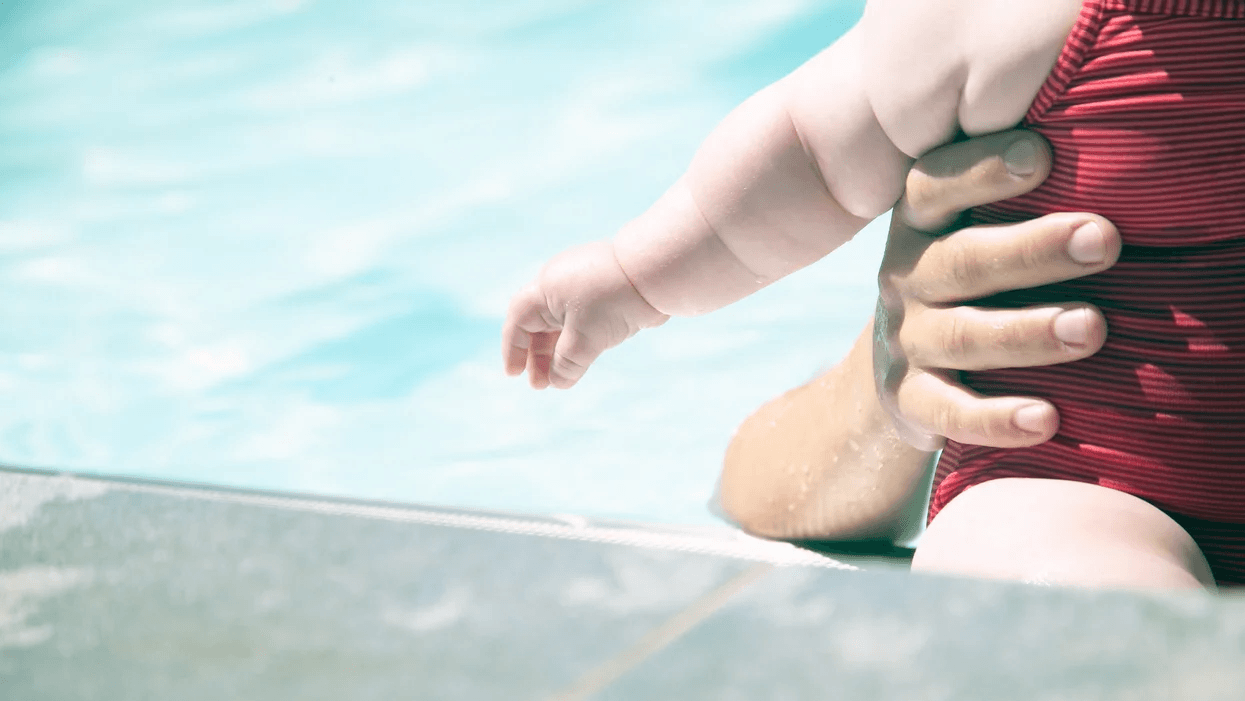 mom holding infant in a pool