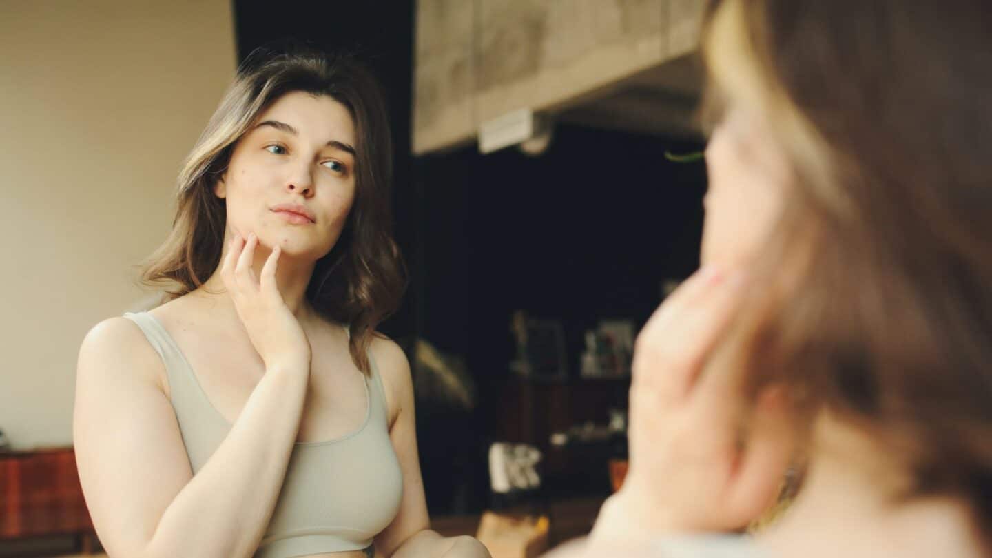 woman looking in mirror contemplating breastfeeding after breast implants