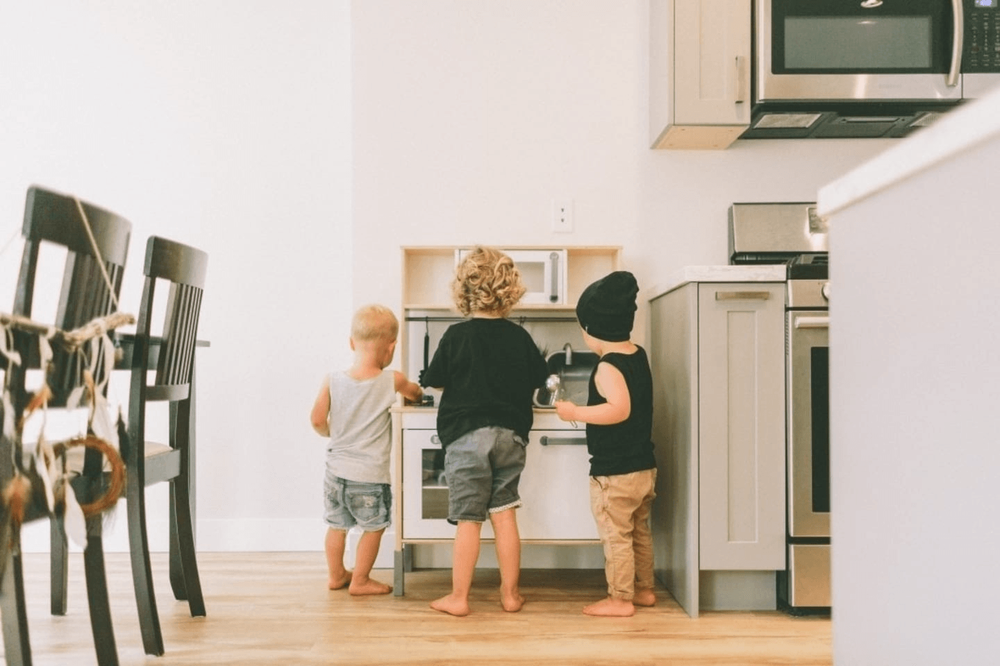 little kids playing in a play kitchen