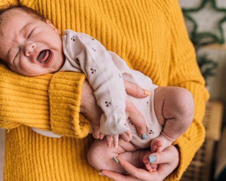 Mother holding crying baby with colic but taking probiotics for colic might help Motherly
