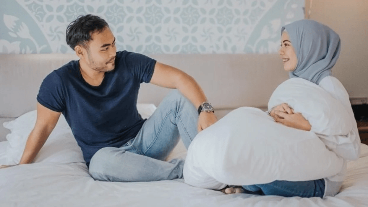 couple sitting on a bed, talking