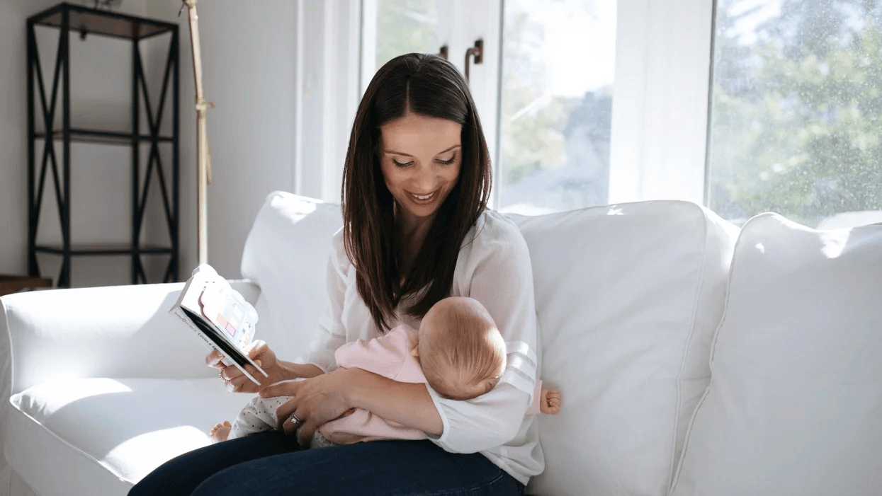 mom reading a book to a 2-month-old