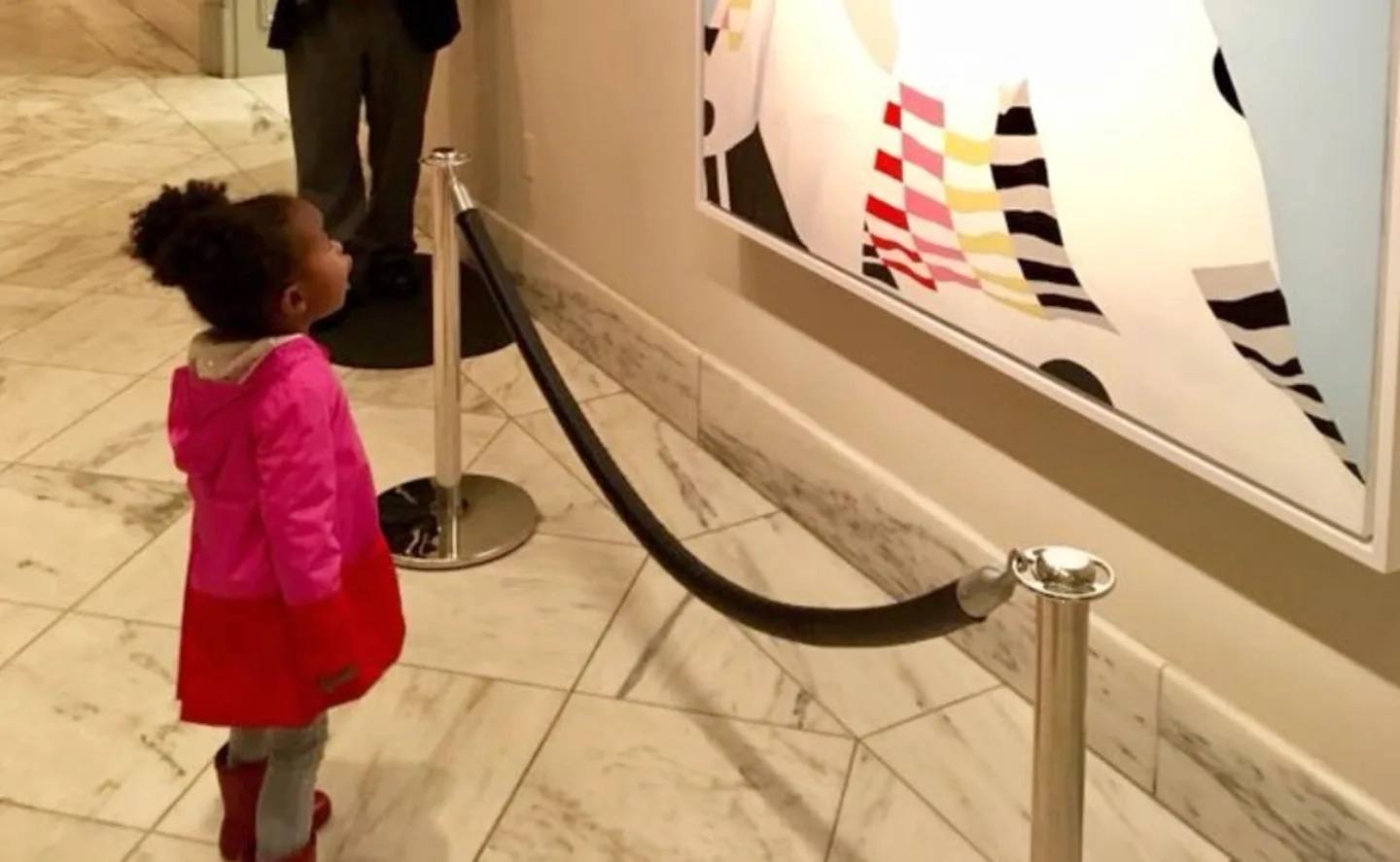 little girl looking up at a portrait of michelle obama
