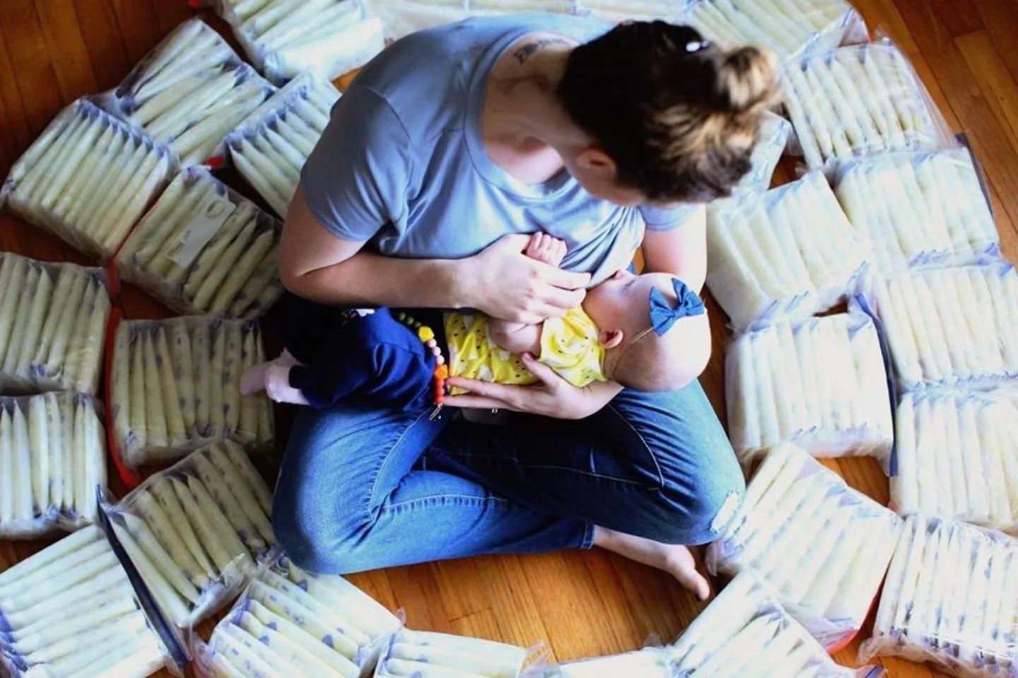 mom feeding baby surrounded by pumped bags of milk