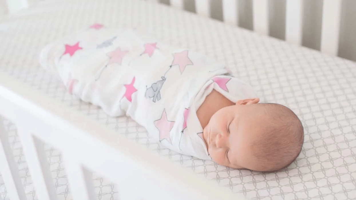 swaddled baby sleeping in a crib