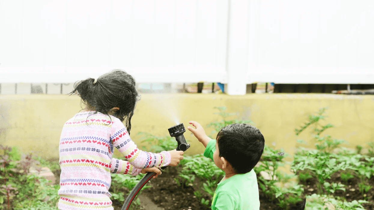 siblings playing with a sprinkler