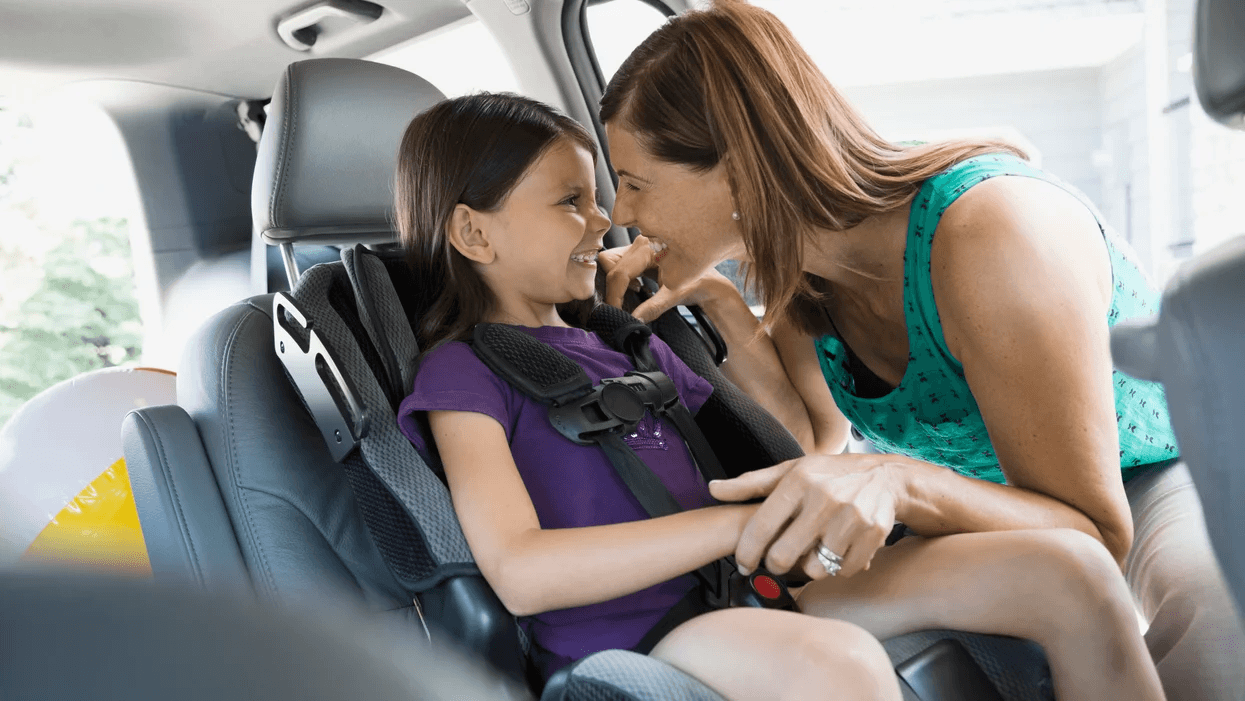 mom laughing with daughter in a booster seat - keeping kids in car seats