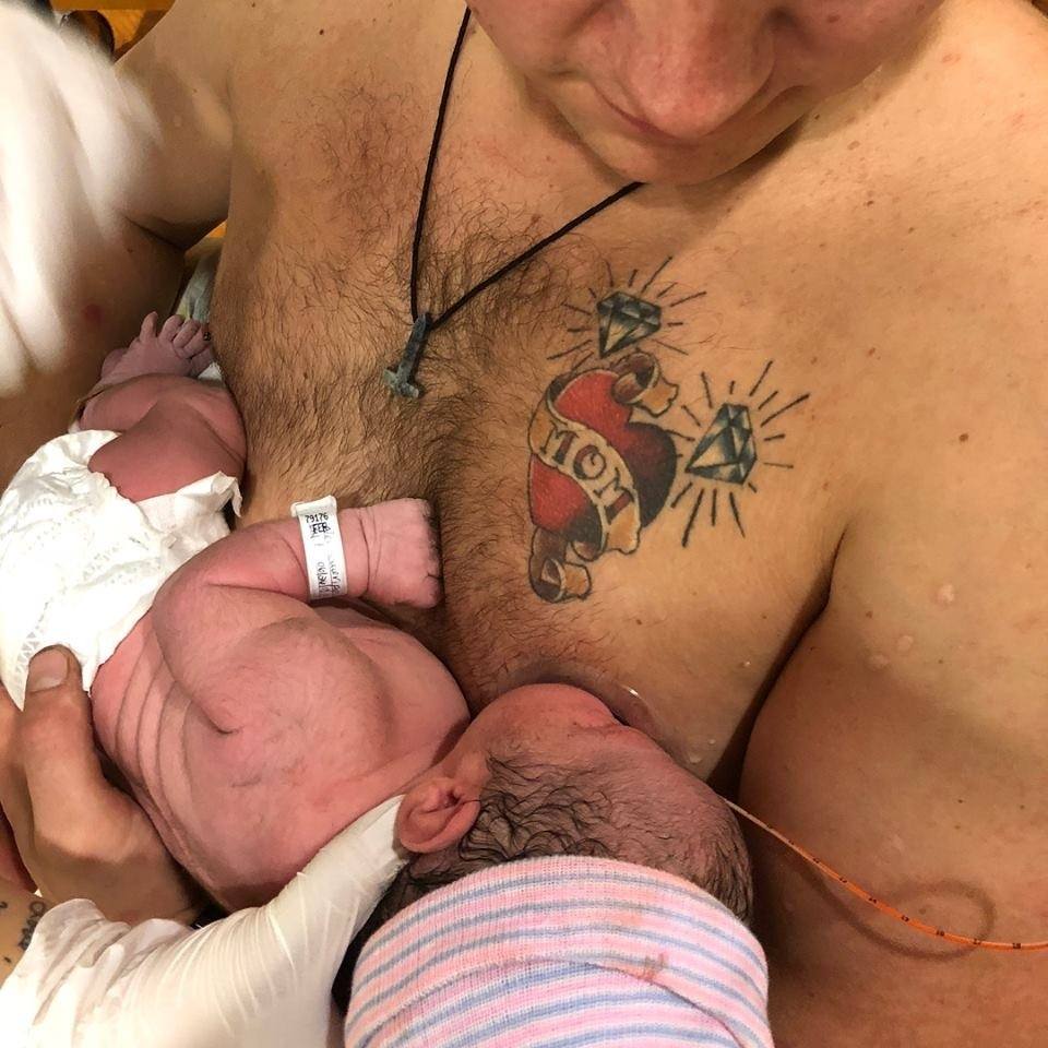 Bare Chested Man holding a new born baby