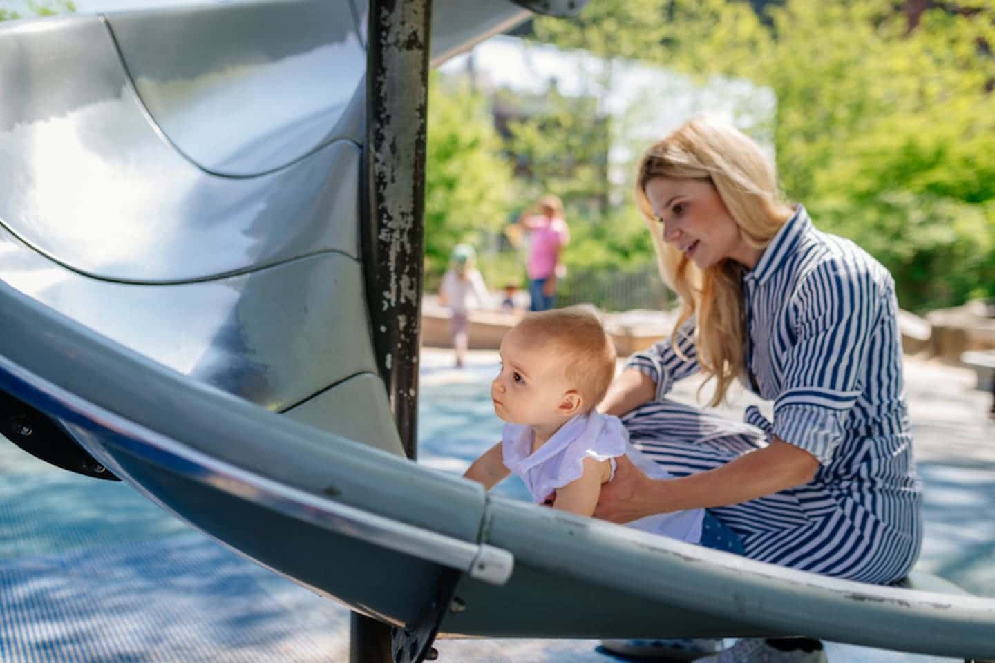 woman and baby playing on the slide