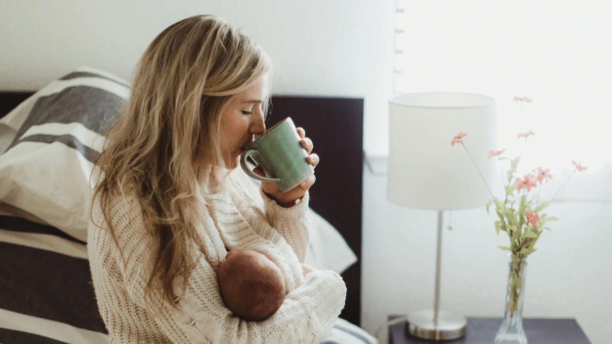 mom holding baby and drinking a cup of coffee