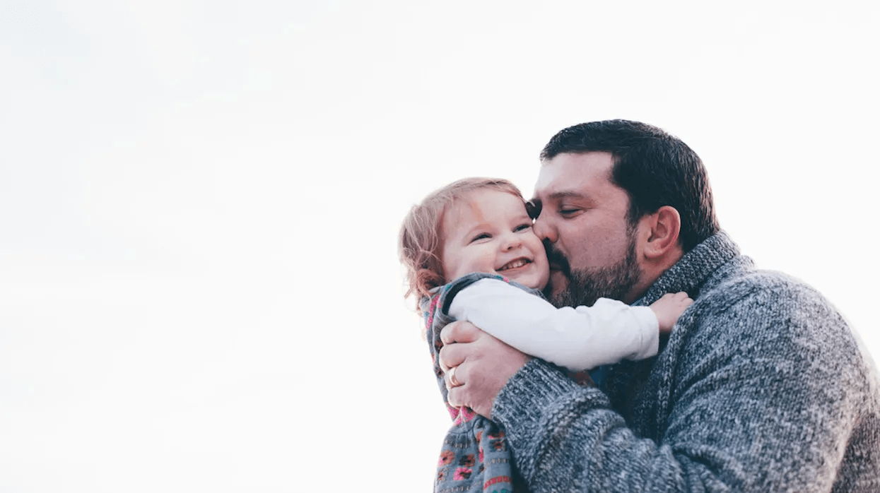 dad kissing daughter on the cheek