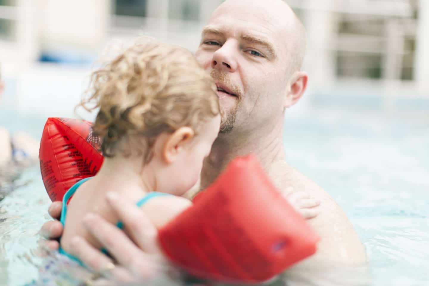 man carrying his child in a pool