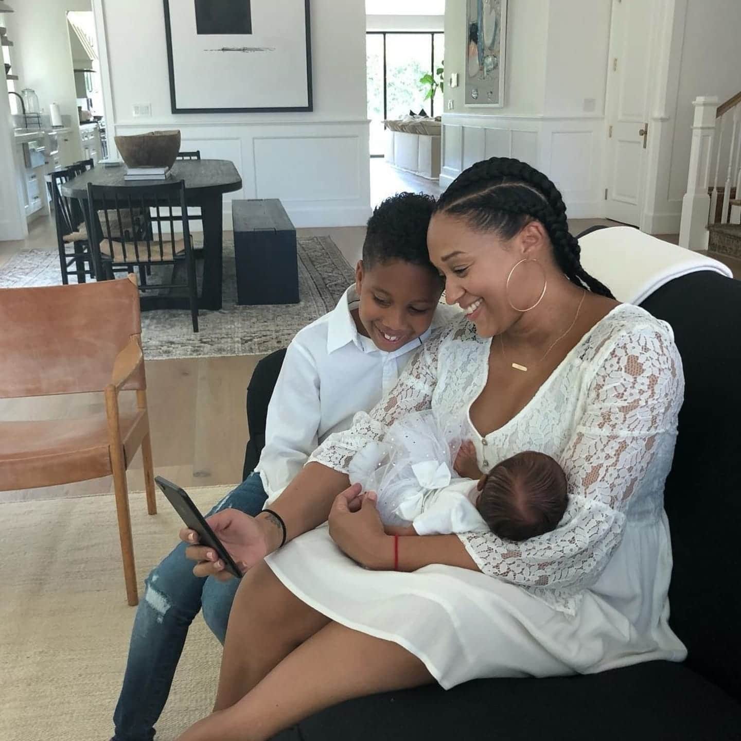 Tia Mowry sitting with her child and carrying her baby
