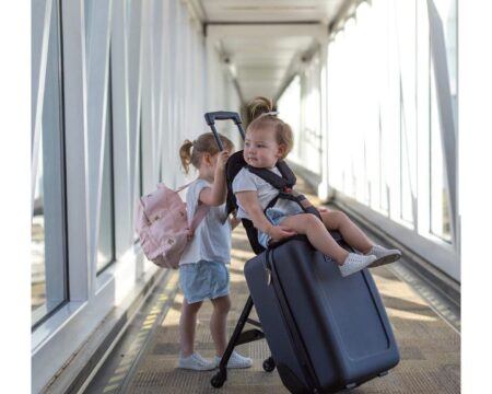 baby riding a suitcase at the airport, one of motherly's best products for baby's first flight