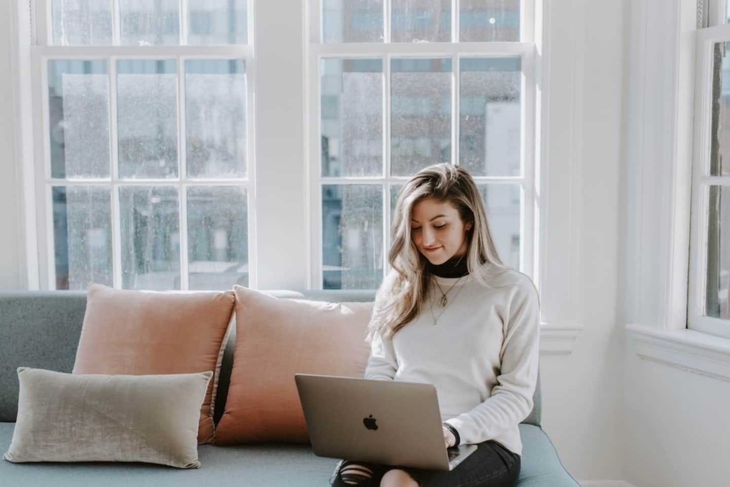 woman sitting near the window using her mac book