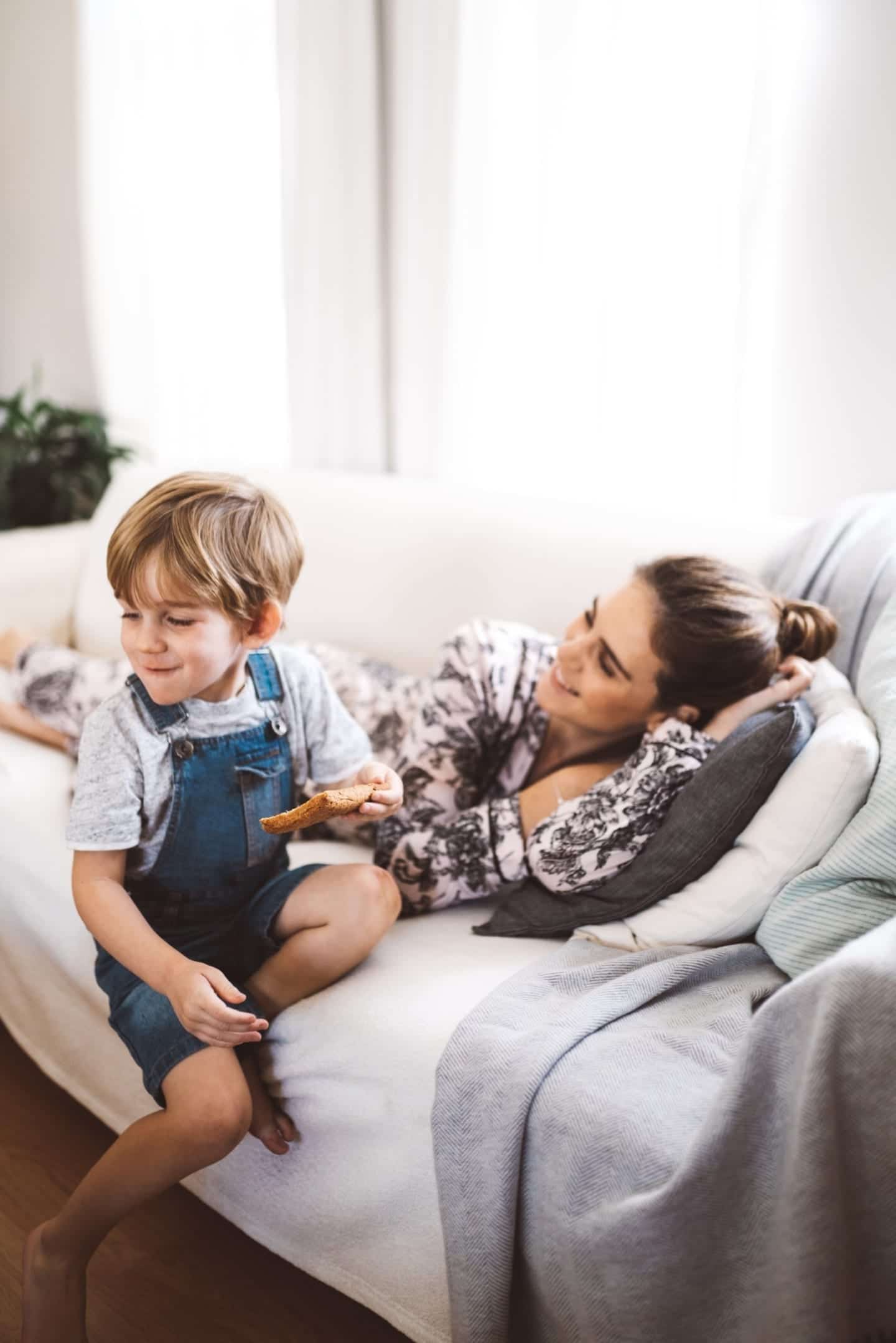 mom laying down on the couch and looking at child