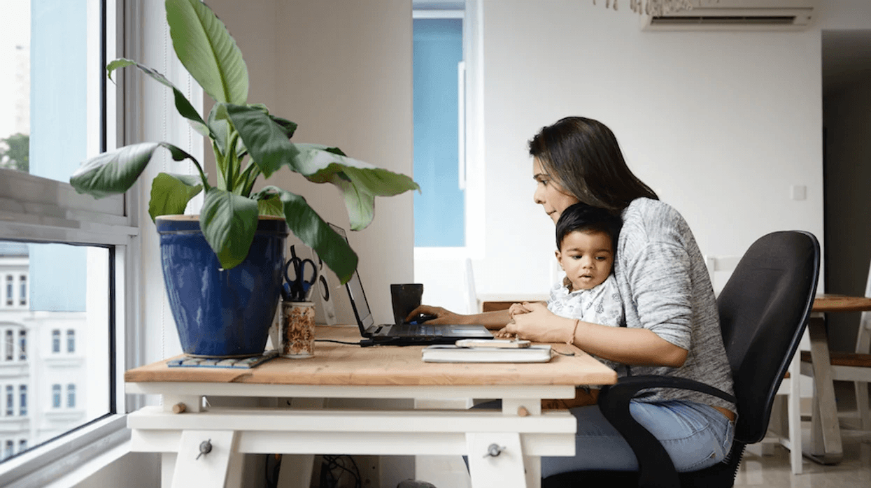 mom working on a computer while child sits on her lap