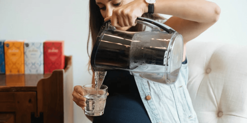 pregnant woman pouring herself a glass of water