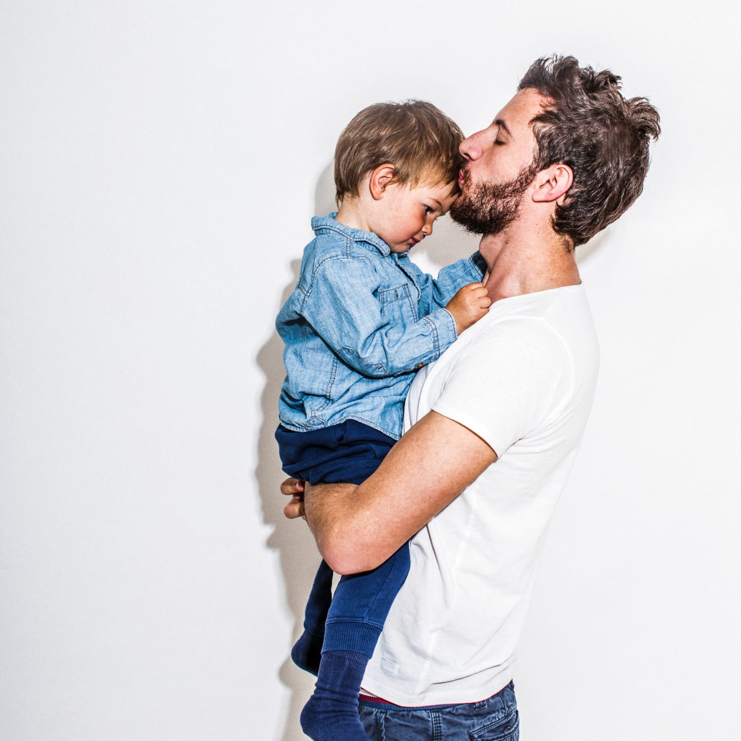 man carrying and kissing child's forehead