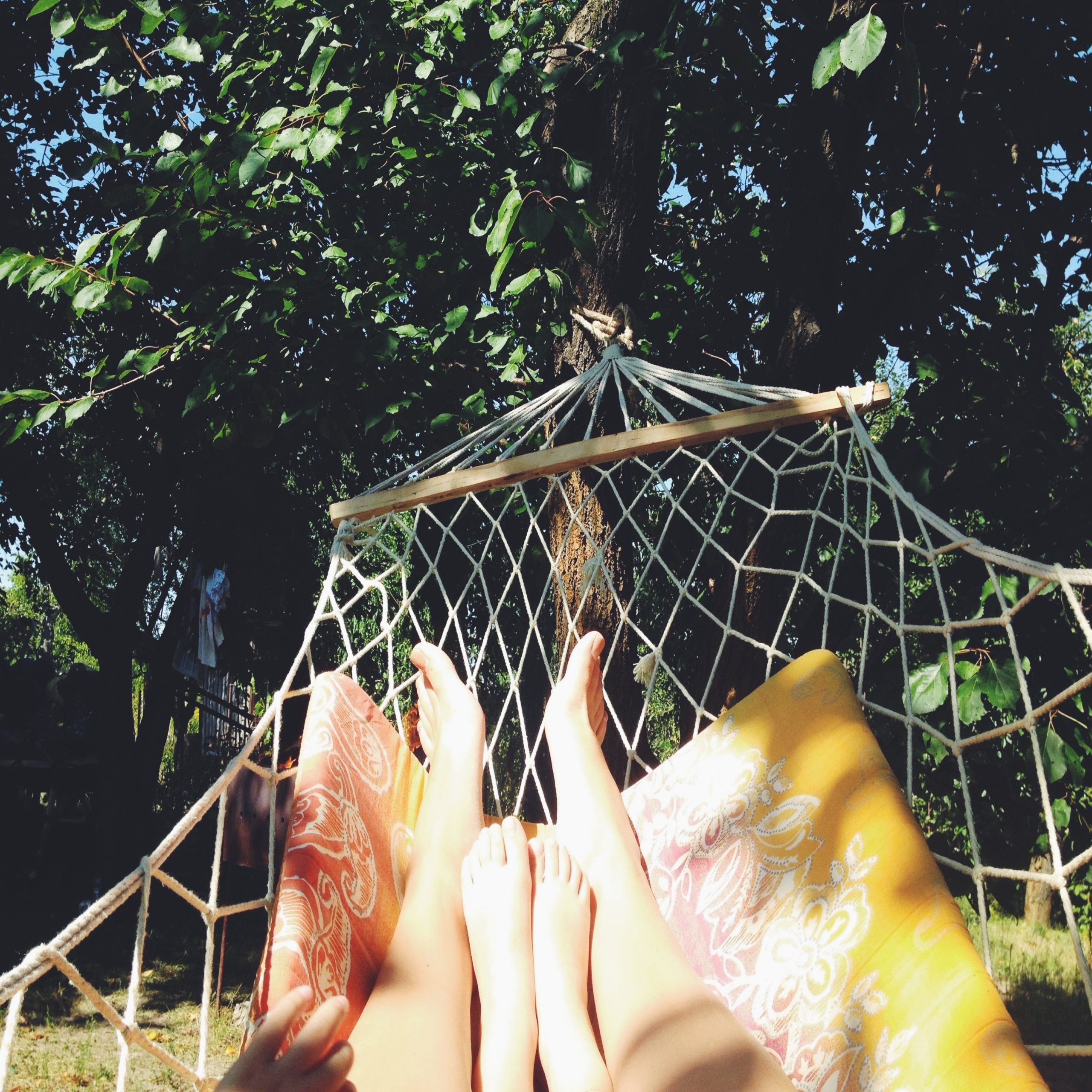 adult and child legs shown on hammock in summer