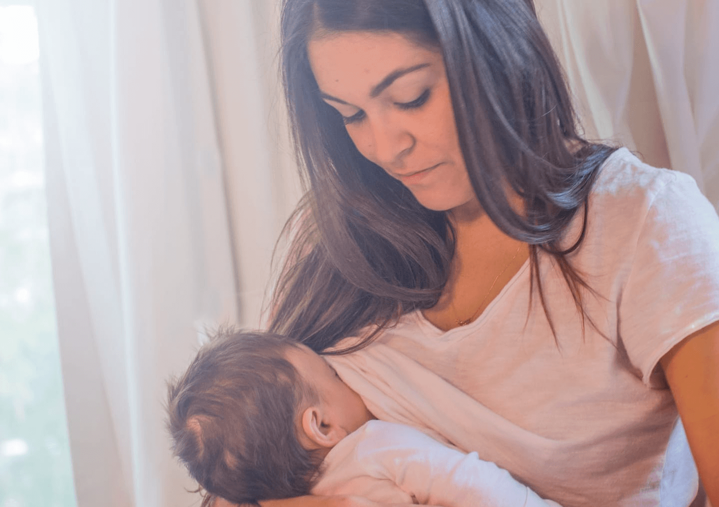 woman breastfeeding baby under her shirt