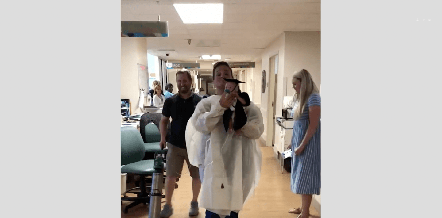 nurse holding a baby wearing a cap and gown