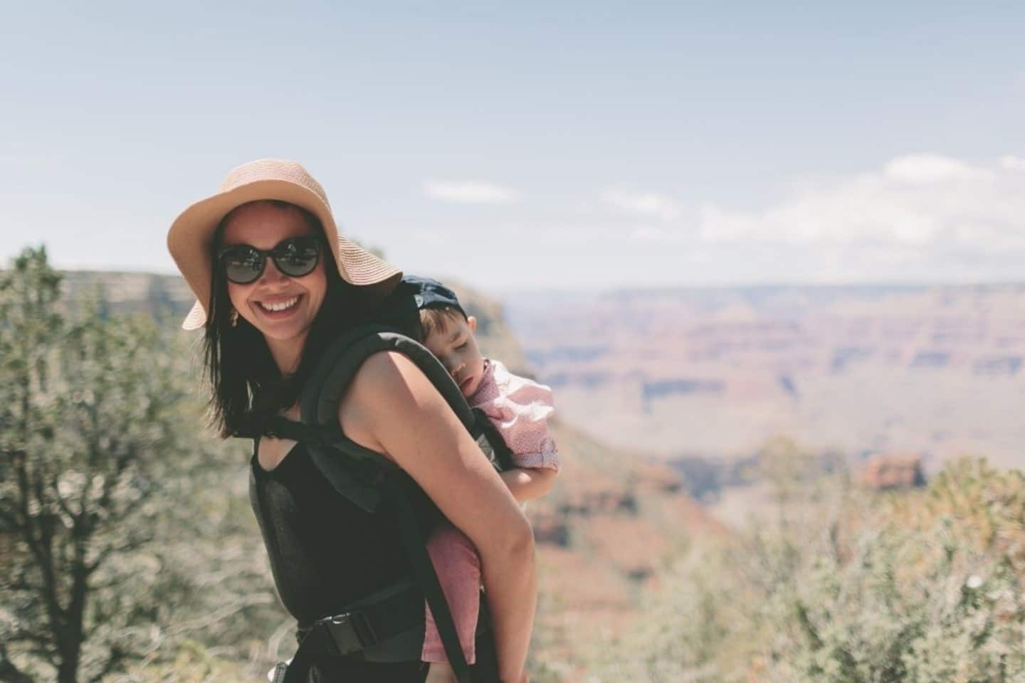 mom going for a hike while carrying her sleeping toddler on her back