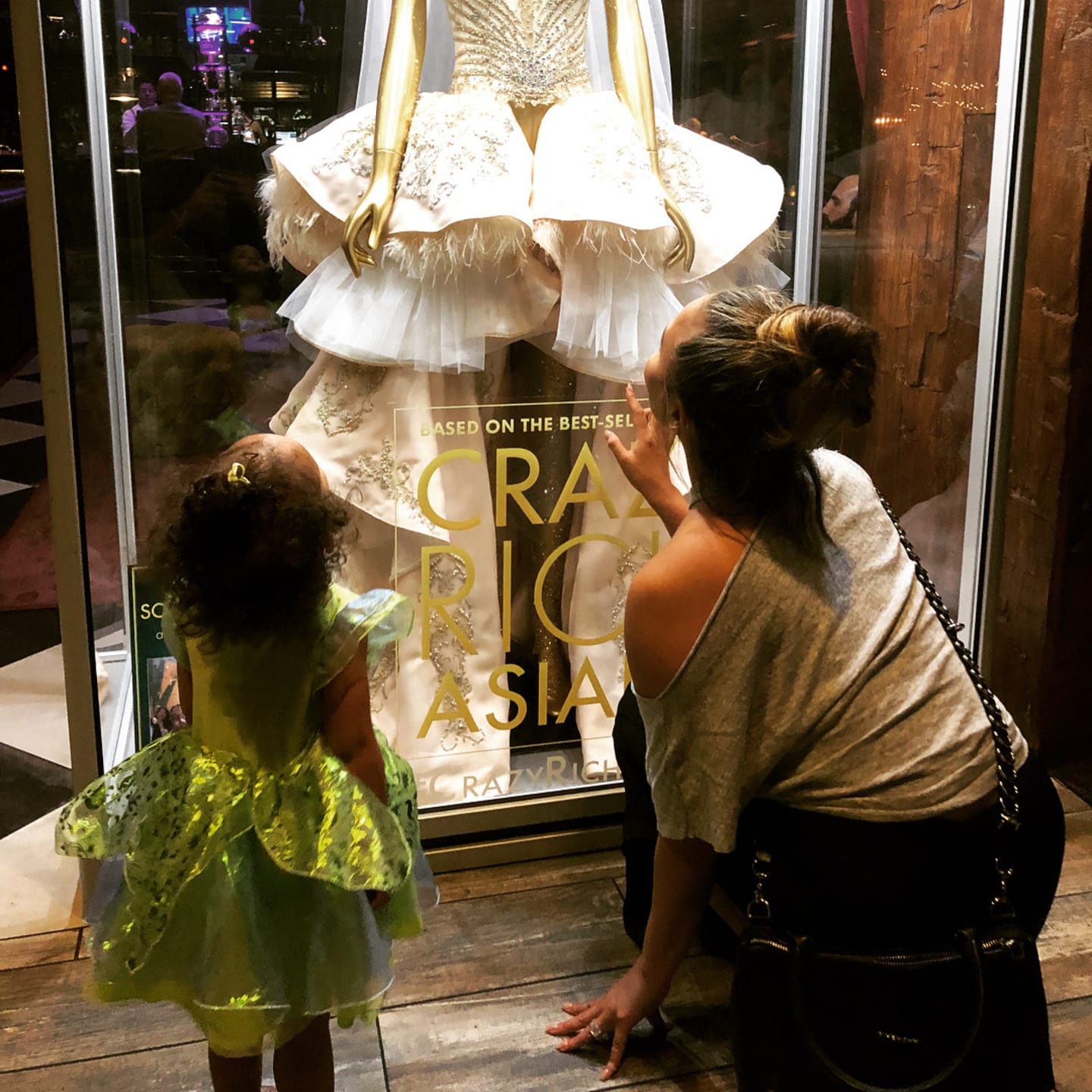 Chrissy Teigen and daughter, Luna, looking through a window shop