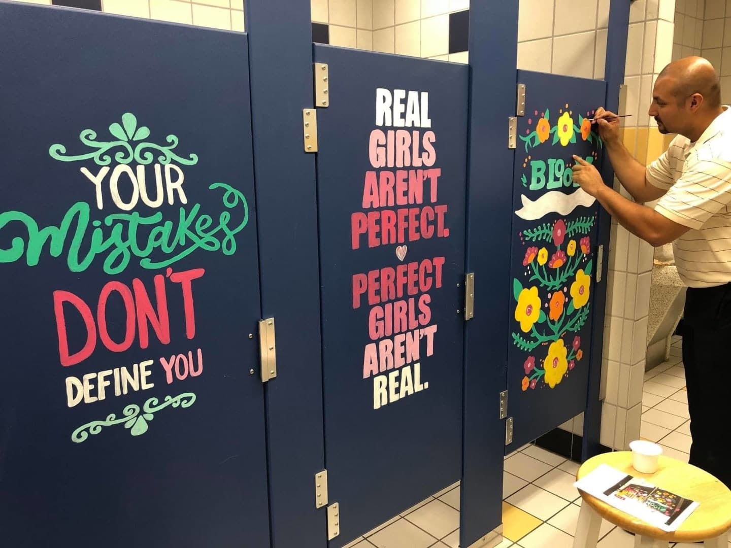 man painting bathroom stall doors