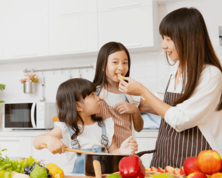 woman cooking with daughters in kitchen Motherly