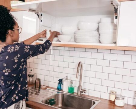 woman putting plates away simple ways to organize your home Motherly