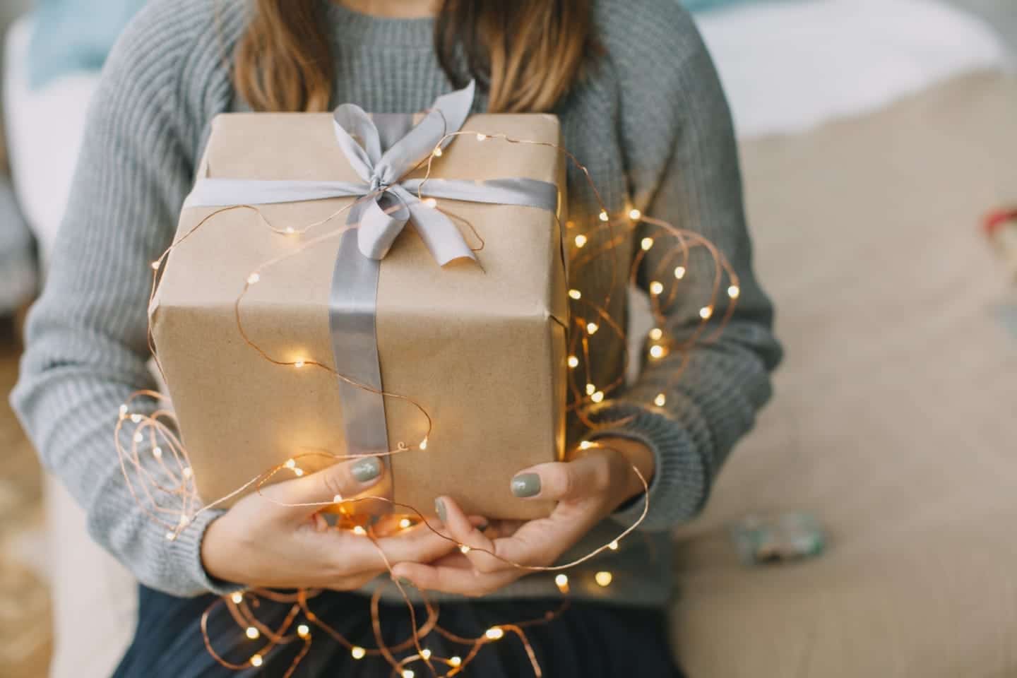 woman holding christmas present wrapped in lights