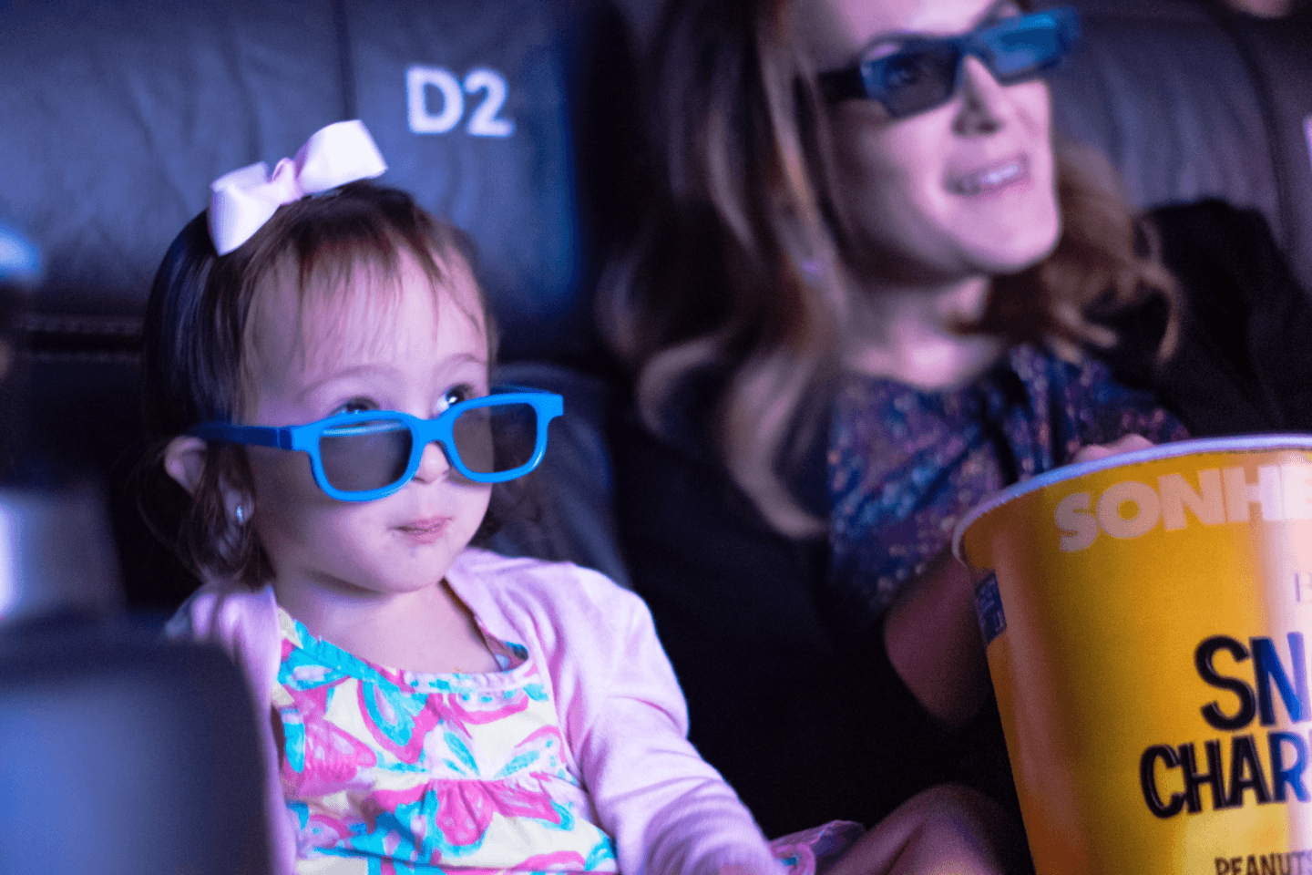 little girl at the movie theater wearing 3D glasses