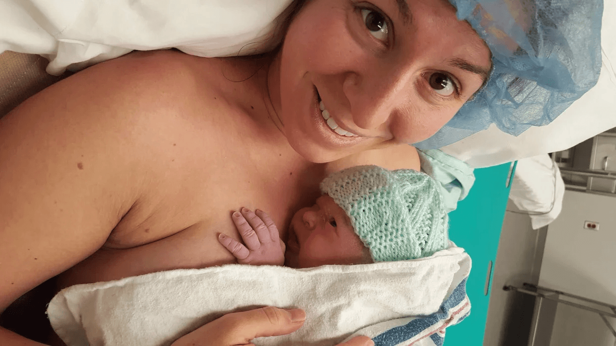 woman smiling at the camera while doing skin to skin after giving birth