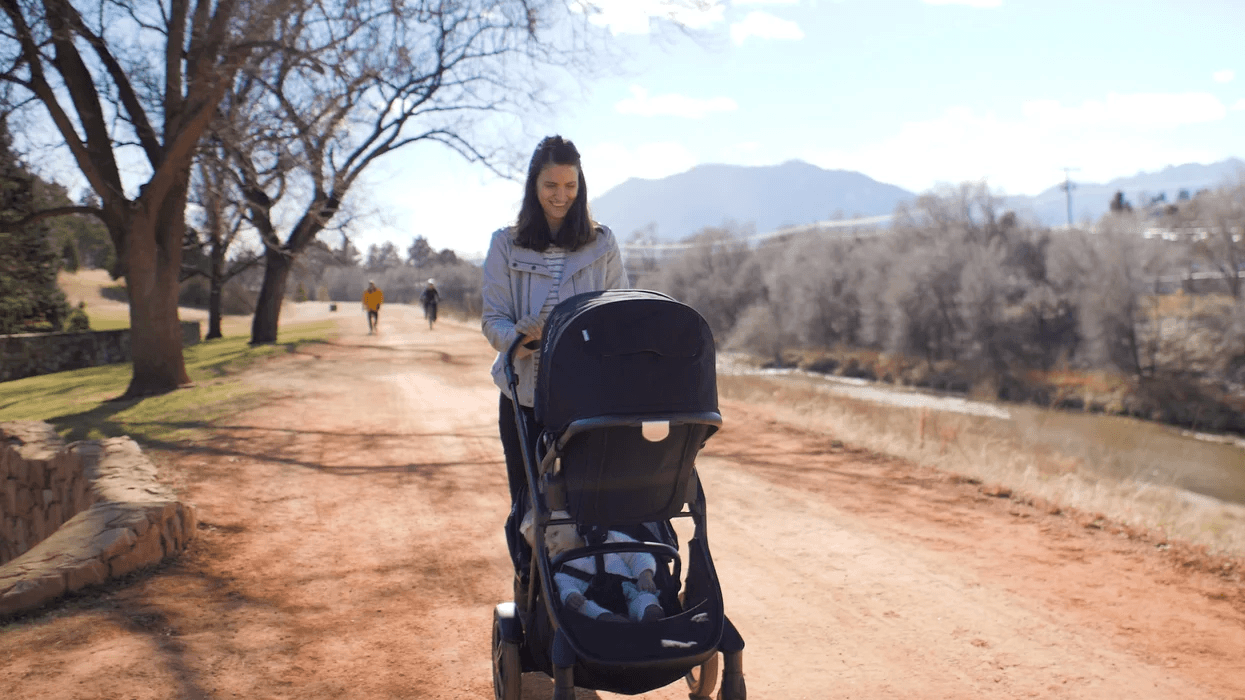 mom pushing a stroller on a trail
