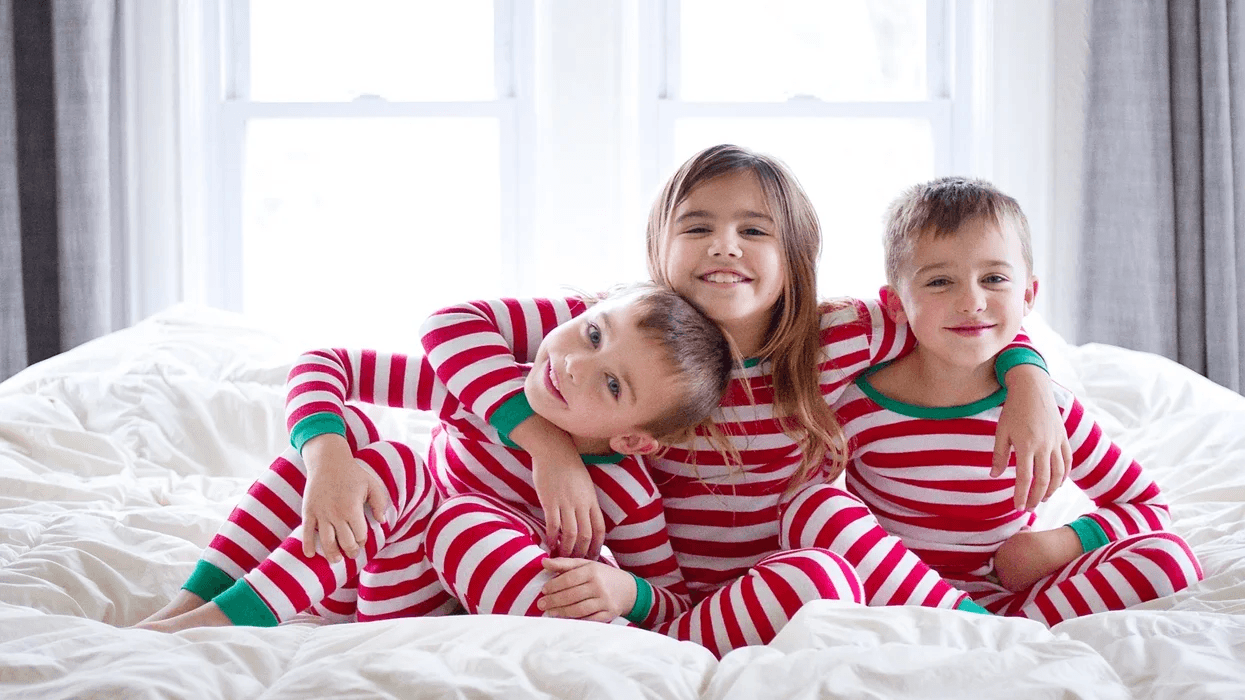 siblings wearing matching holiday pajamas