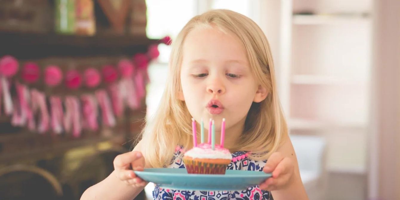 little girl blowing a candle on a birthday cupcake-birthday on a holiday