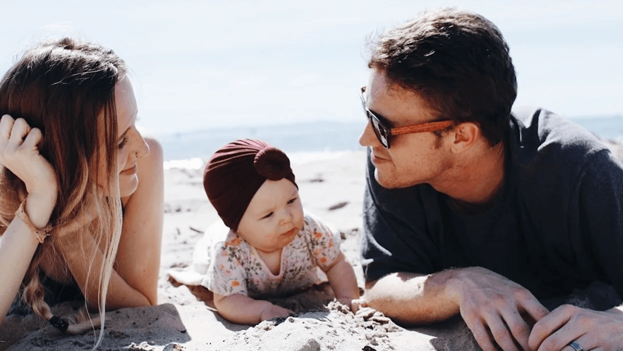 couple laying on a beach with their baby