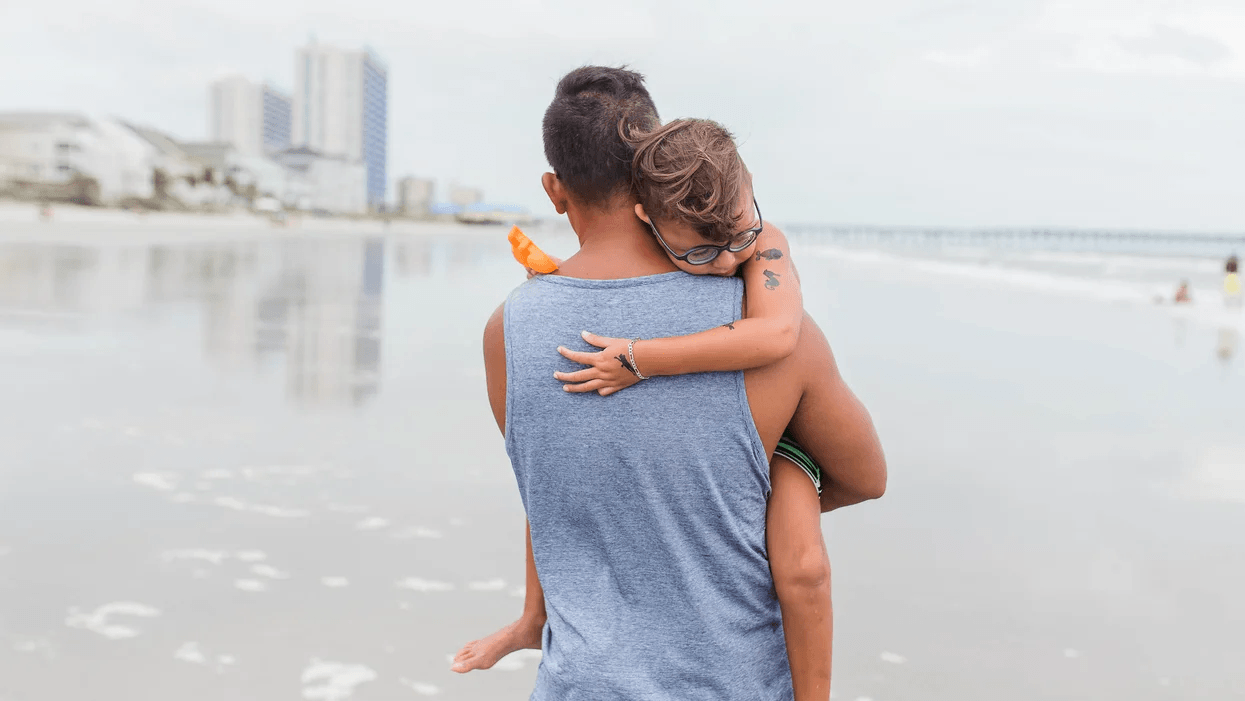 dad carrying son on beach