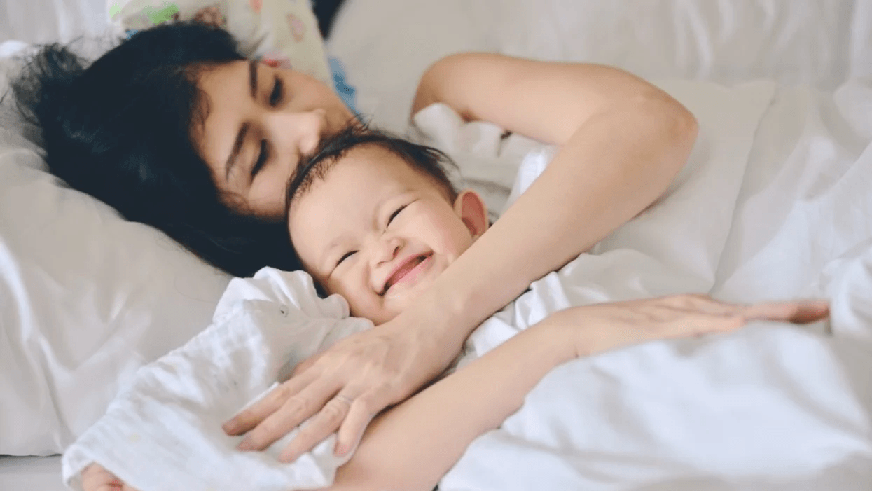 mom hugging a smiley baby in bed