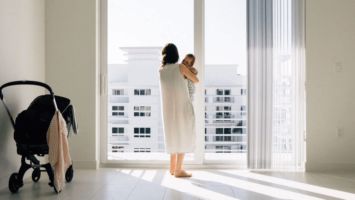 mom holding baby against window doors