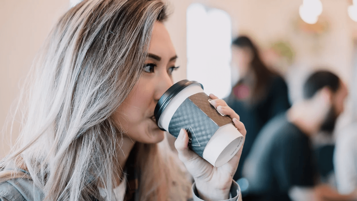 woman drinking coffee from a to-go cup