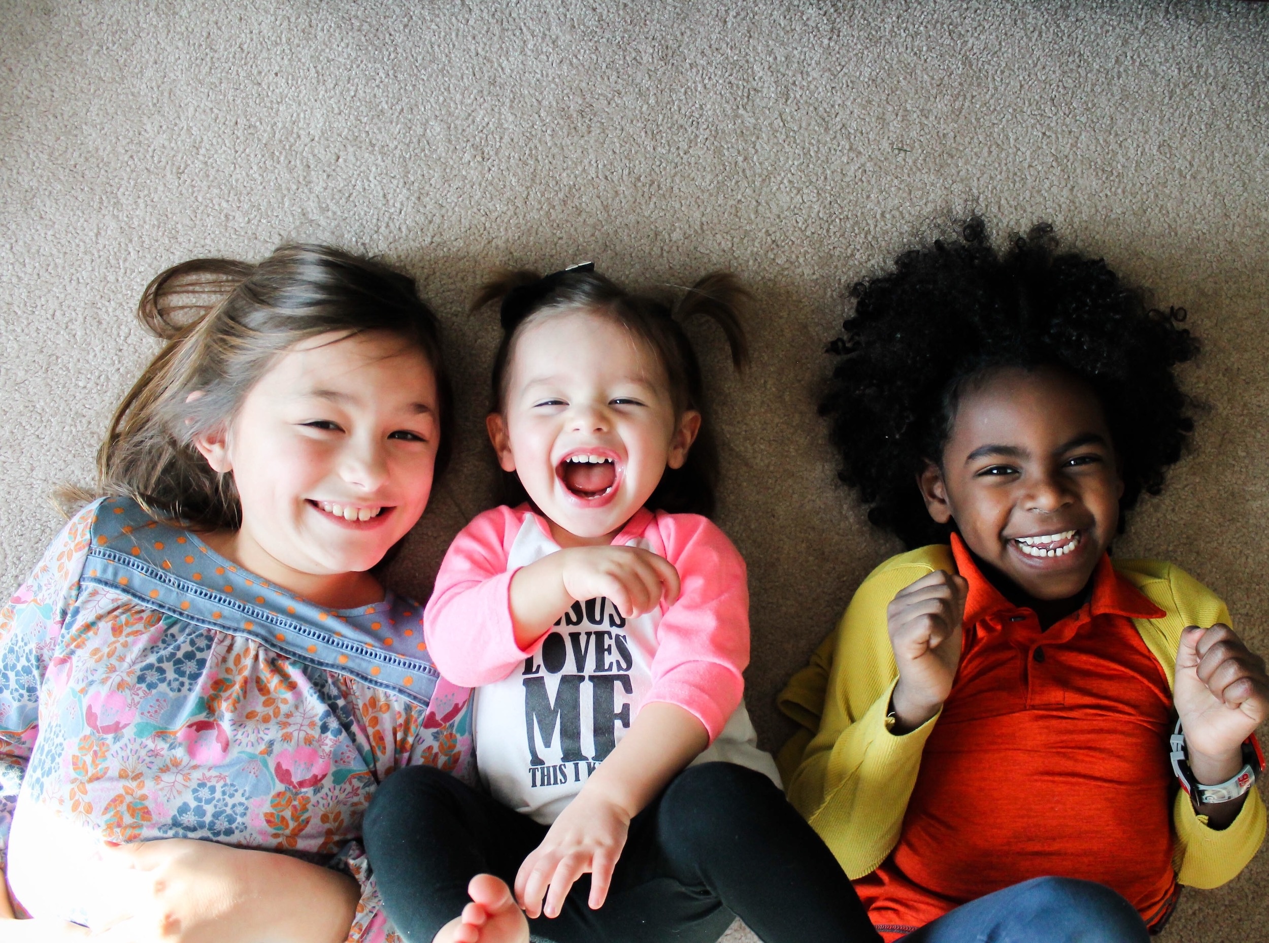 three kids laughing and lying down together- half siblings are real siblings