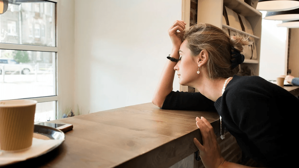 woman resting head against hand in a cafe