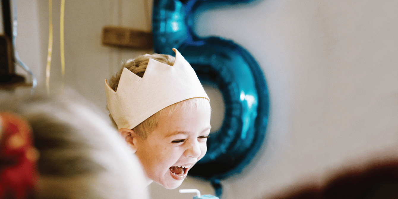 little girl laughing wearing a paper crown - fiver party