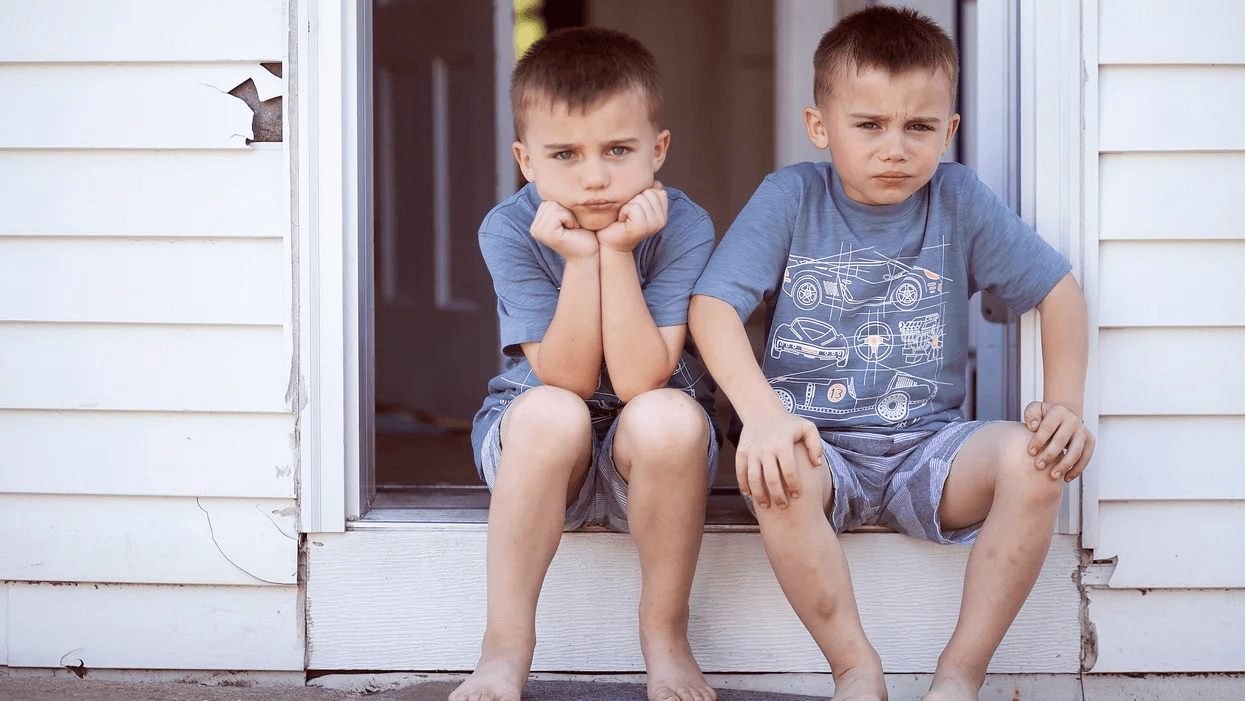 twin boys sitting outside the front door