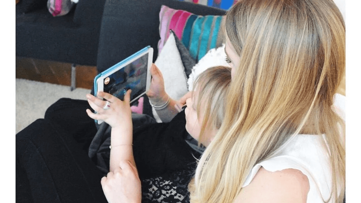 toddler playing on a phone in mom's lap