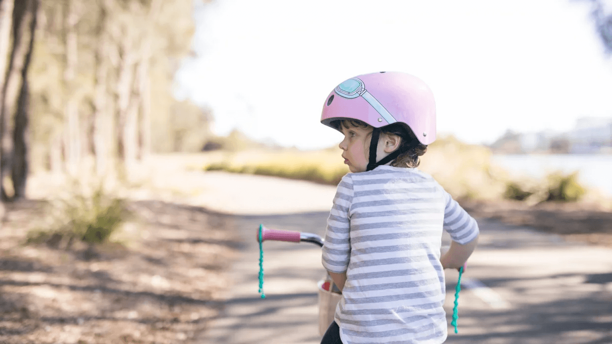 little girl wearing a pink helmet on a bike